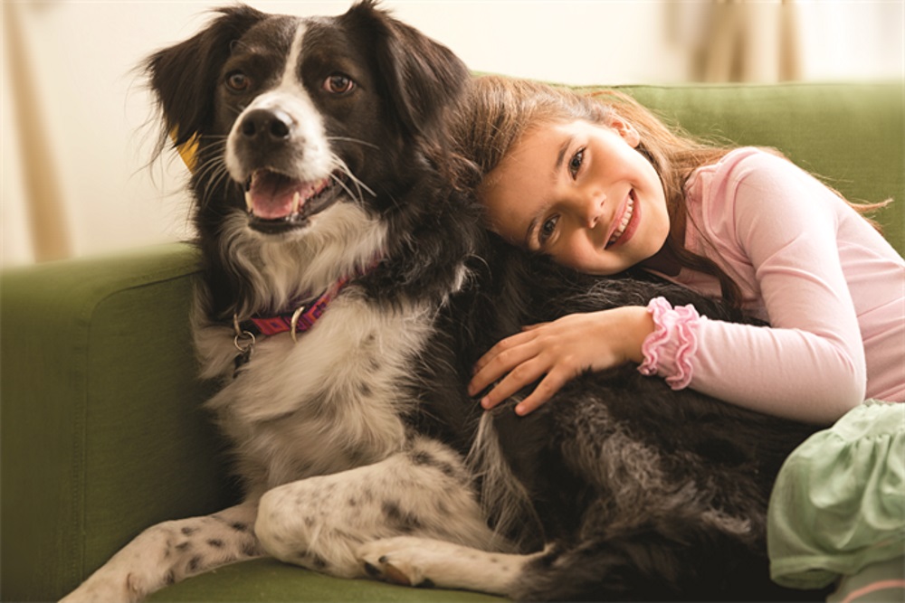 Mädchen kuschelt sich an Hund